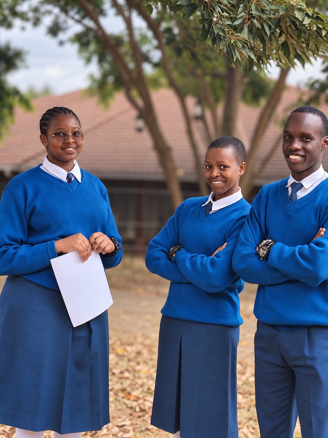 Three students in school uniform standing together after a NenaHub speaking club session