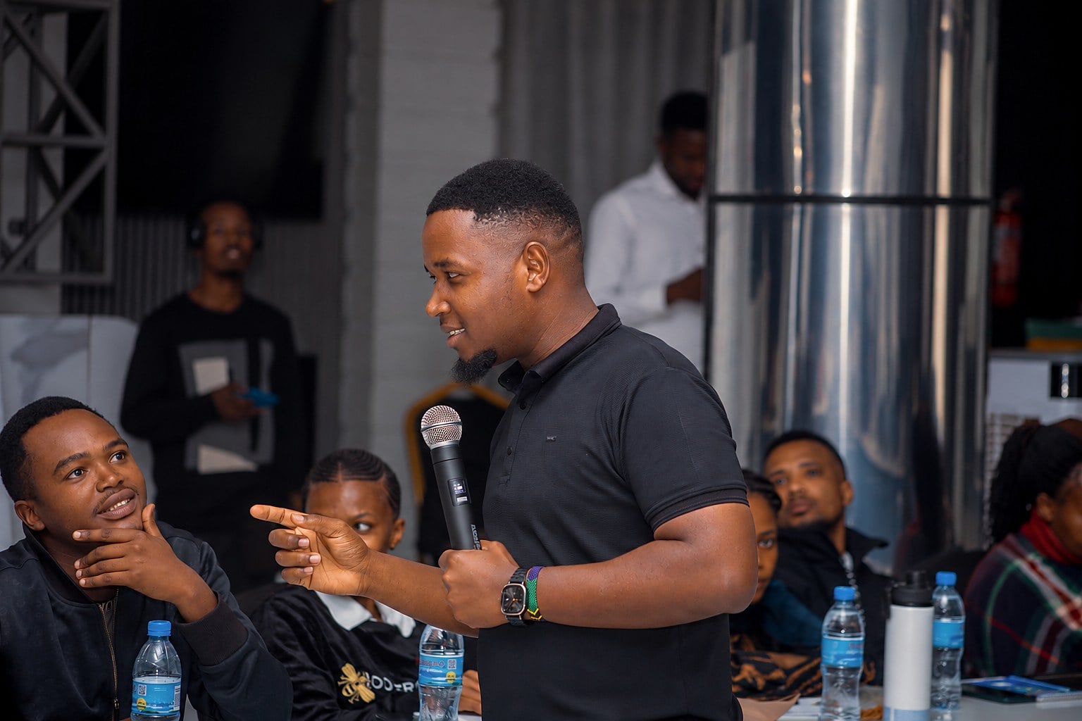 A NenaHub facilitator with a microphone leading a workshop while participants listen